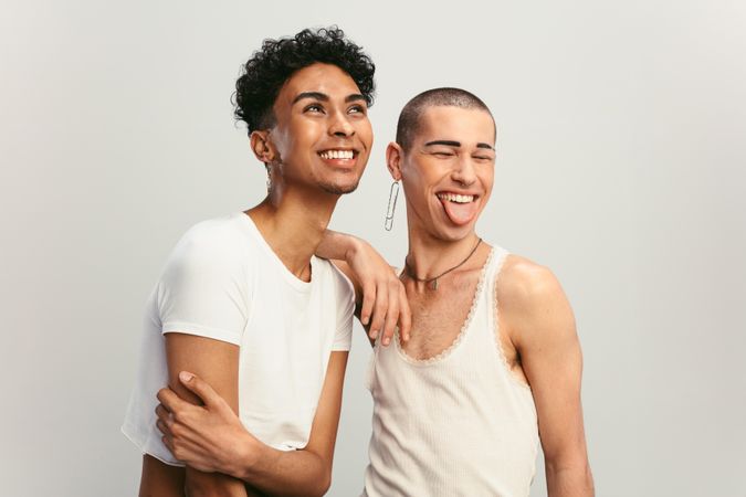 Male couple smiling on light background.