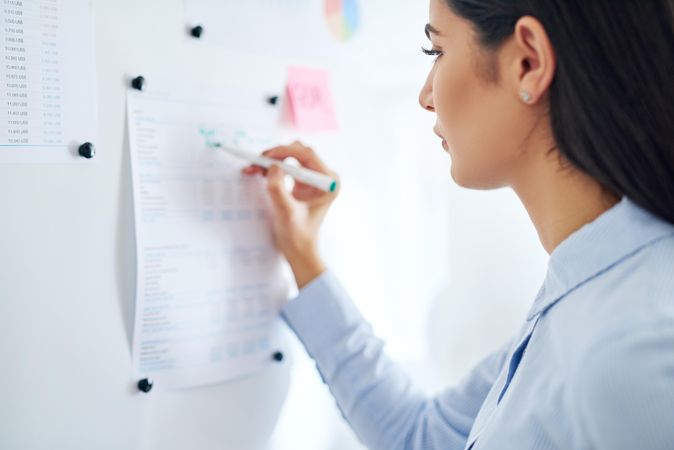 Woman writing on chart on paper pinned to board
