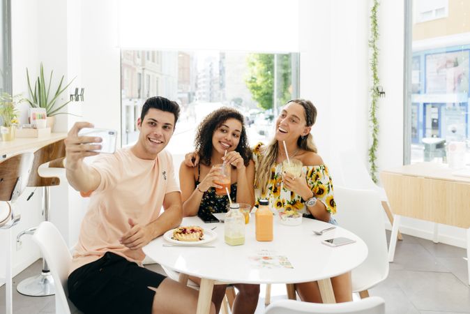 Man taking selfie of friends in cafe