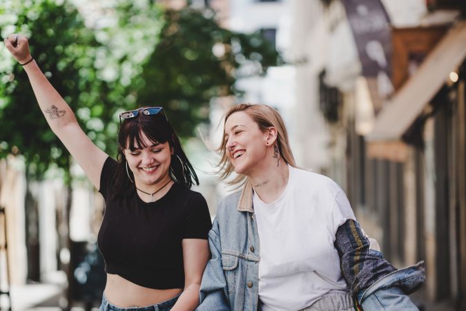 Lesbian couple with LGBT flag walking on street