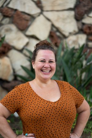 Portrait of woman smiling and looking at camera with hands on her hips