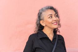 Older woman with gray hair smiling in the street.