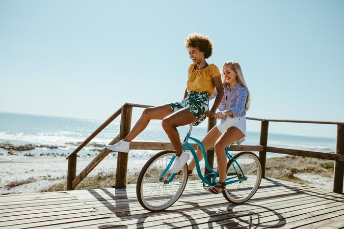 Woman riding a bicycle with her friend sitting on the handlebar