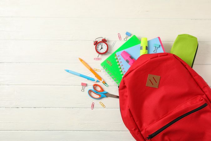 Flat lay composition with backpack and school supplies on wooden background