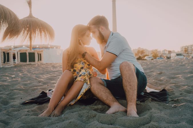 Tender couple kissing in sunlight on beach
