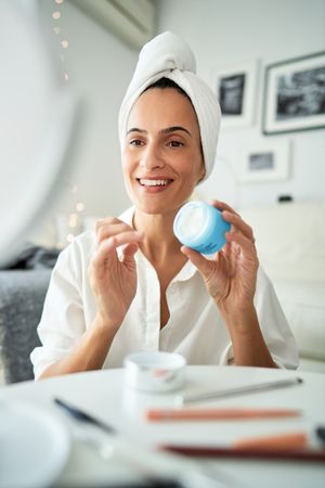Happy woman with facial cream in morning time