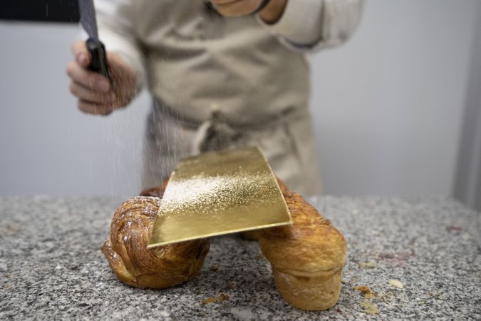 Confectioner decorating buns with sugar powder