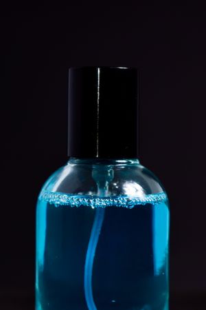 Close up of light blue perfume bottle in dark studio