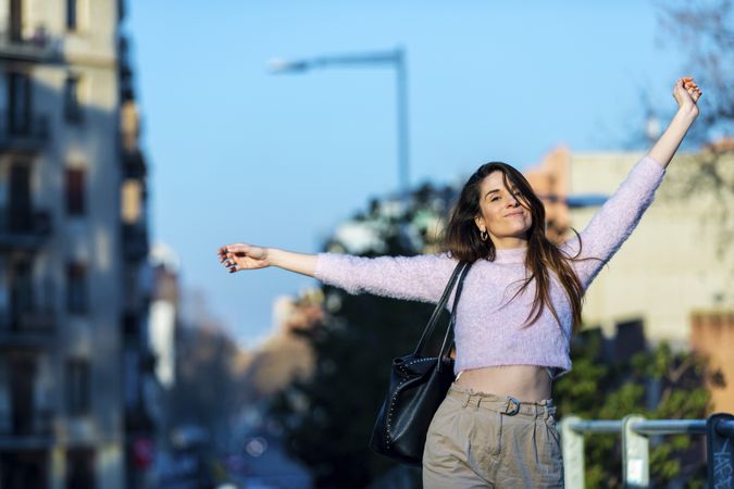 Woman in casual wear with arms up on a sunny day