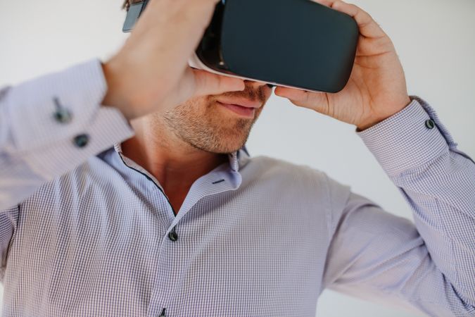 Shot of young man using the virtual reality headset against grey background