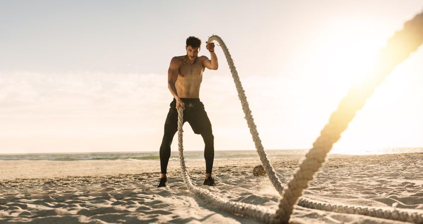Athletic man doing fitness workout at a beach on a sunny day
