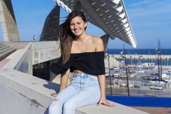Young smiling woman with long hair sitting on promenade against harbor