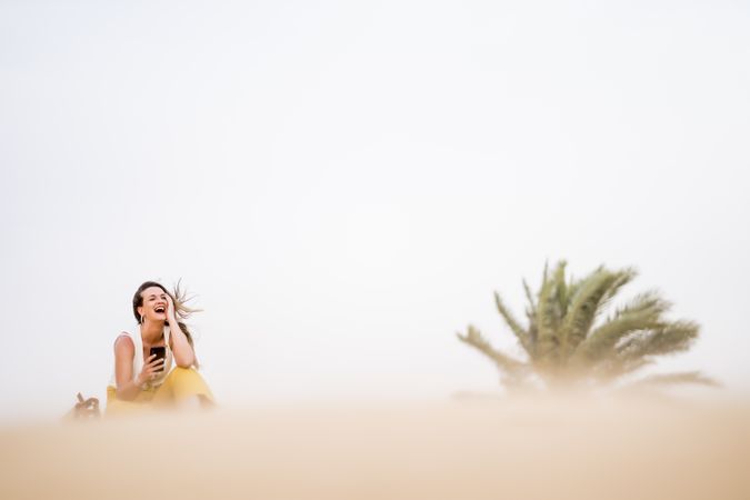 Happy woman using smartphone in desert