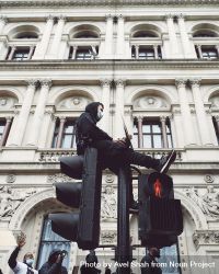 London, England, United Kingdom - June 6th, 2020: Man in mask sitting atop traffic lights 4NE3D5