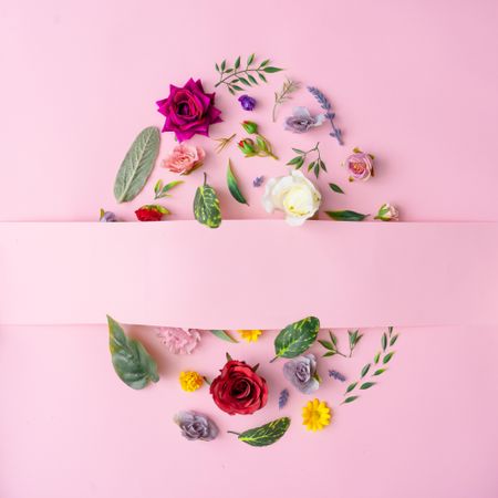 Easter egg shape made with various spring flowers and leaves on pastel pink background