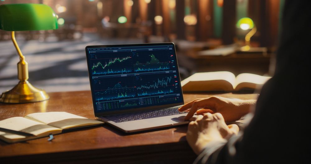 Analytical Business Professional Analyzing Financial Charts on a Laptop in a Classical Library.