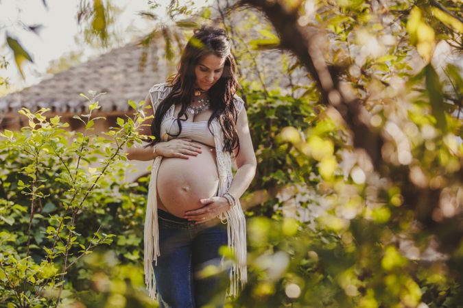 Pregnant woman touching belly in park