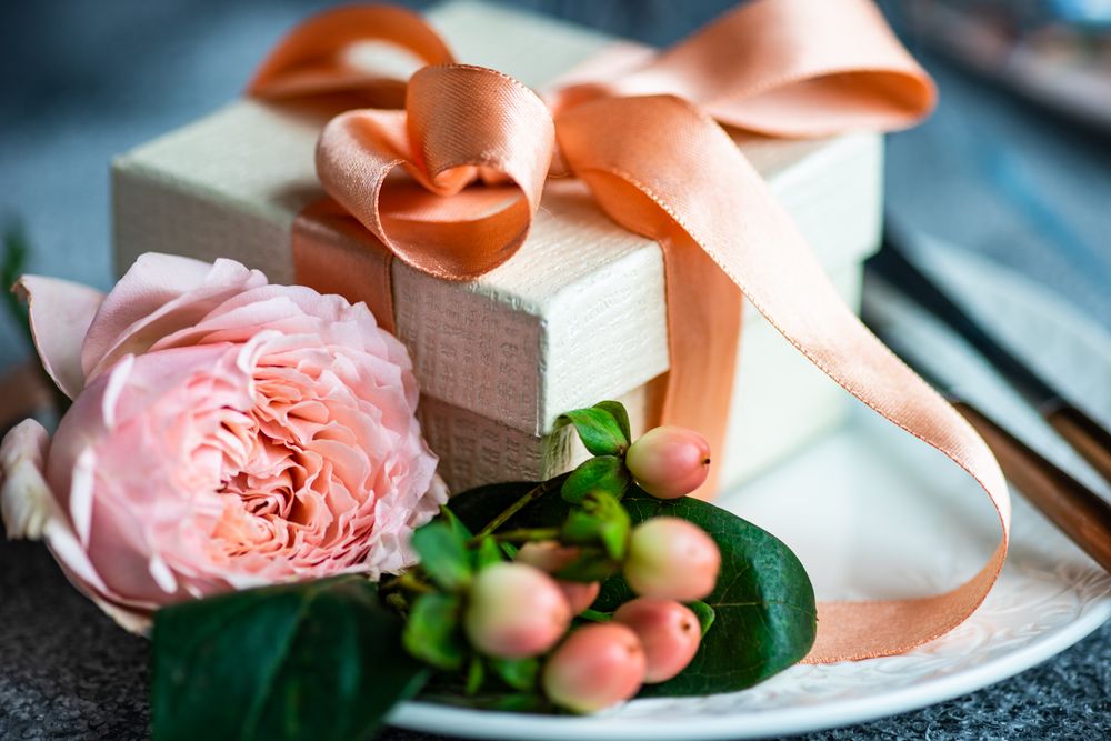 Pink flowers next to gift with pink ribbon