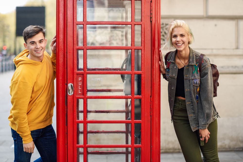 Male and female posing on different sides of a phone booth