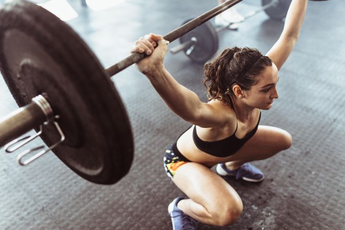 Young woman doing deadlift with heavy barbells in gym