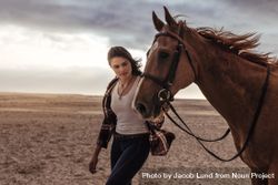 Female equestrian taking a walk with her stallion in evening by the sea 41ypj4