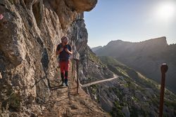 Male hiker with backpack walking on path on cliff