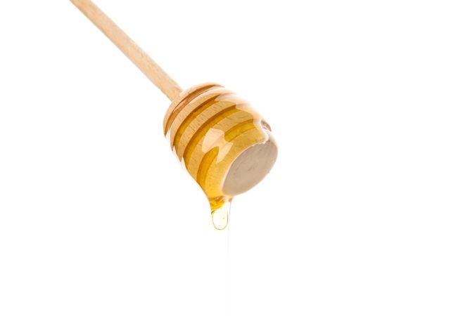 Dipper with honey isolated on plain background, close up