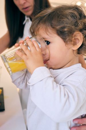 Cute kid drinking orange juice from glass
