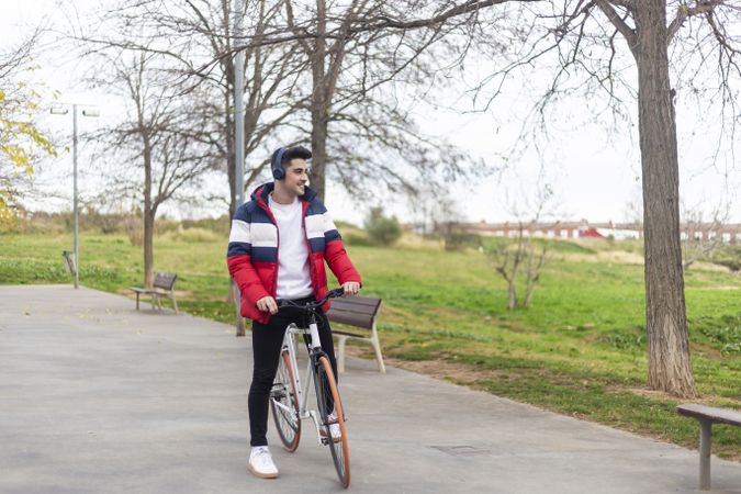Young man enjoying a bicycle ride and listening to music on headphones in the park