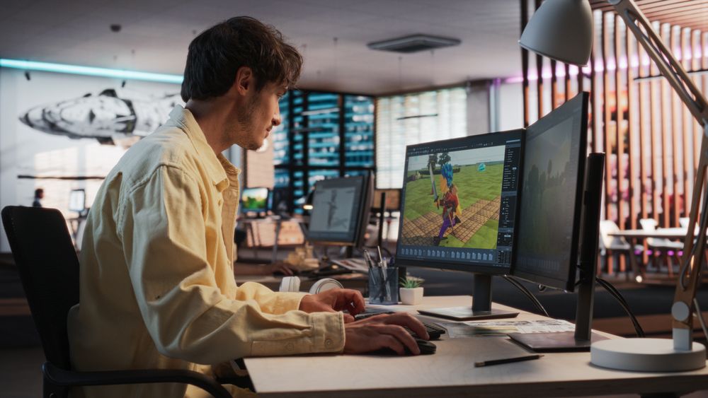 Male Game Designer Using Desktop Computer With 3D Modeling Software To Design Unique Characters And World For Immersive RPG Video Game.