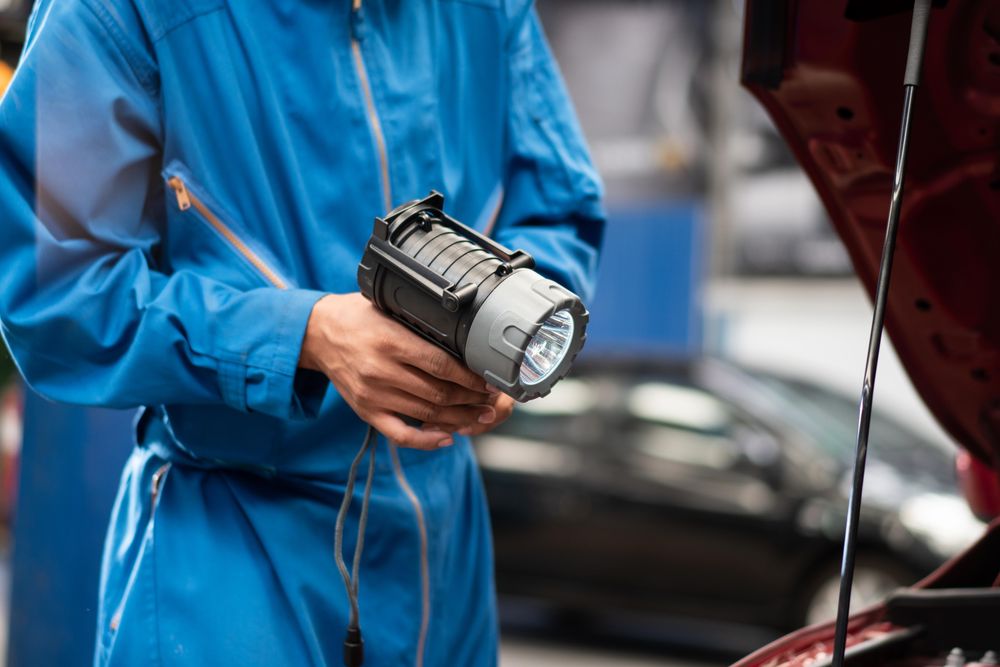 Man with flashlight looking into car engine