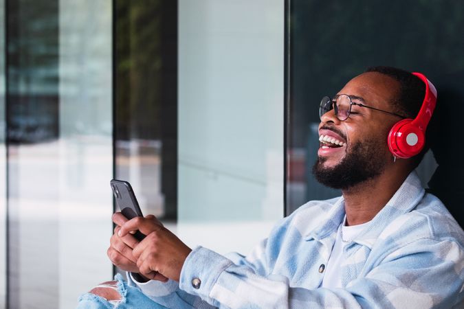 Cheerful Black man with smartphone listening to music