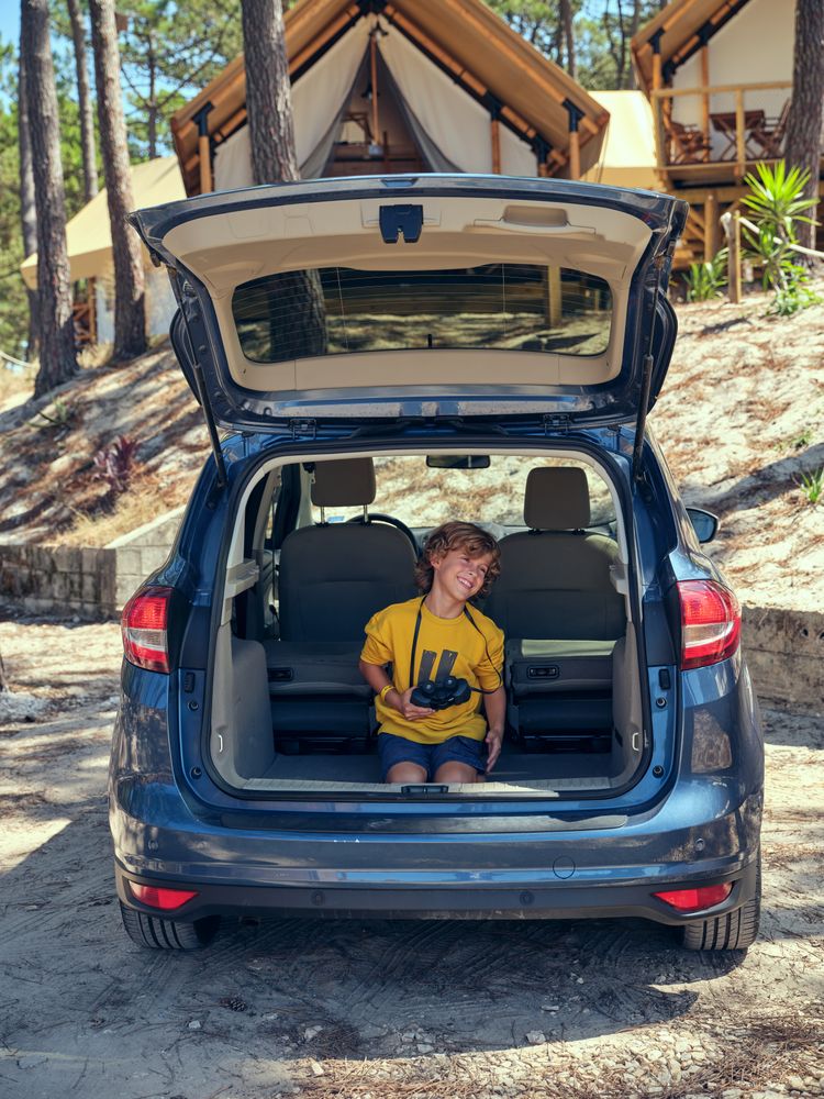 Boy having fun while sitting in trunk near glamping campsite