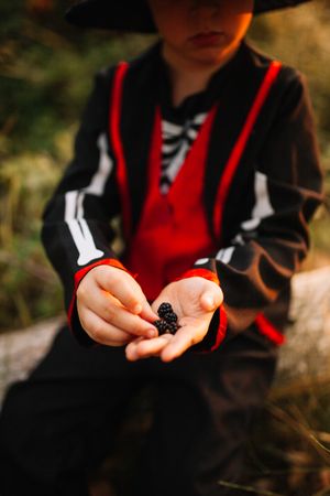 Boy in skeleton costume with berries in his hand