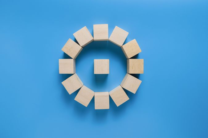a single wooden blocks over circle wooden blocks isolated on blue background. copy space