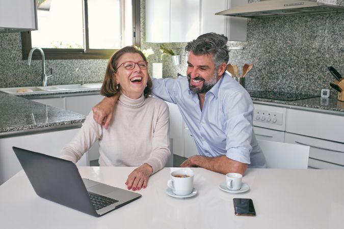 Mother and adult son laughing over video on laptop
