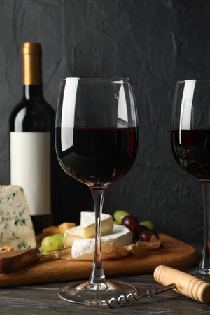 Cheese, grape, bottle and glasses with wine on wooden background, copy space