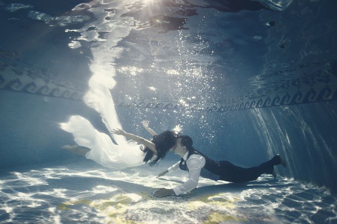 Bride and groom swimming underwater