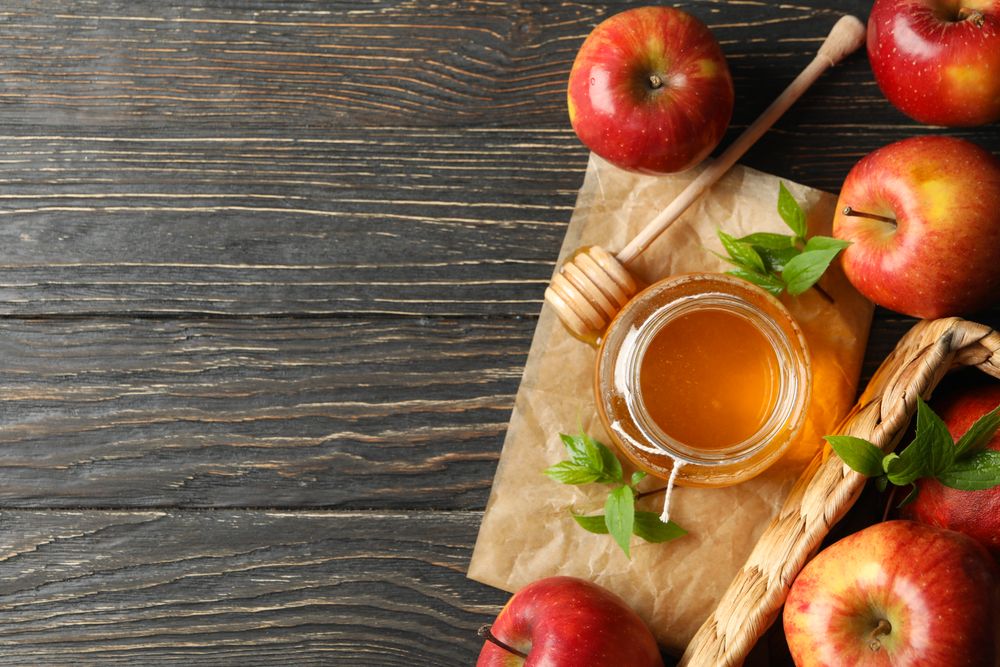 Looking down at pot of honey with dipper and apples with copy space