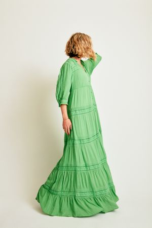 Woman in long green dress standing in studio looking away