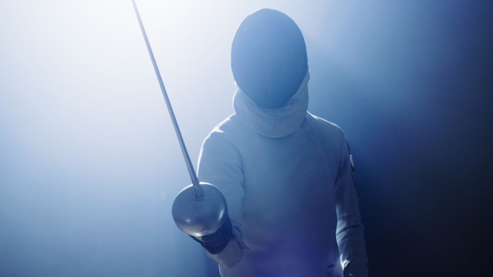 Fully Equipped Fencer Puts Stands in the Spotlight while Darkness is Around Him.