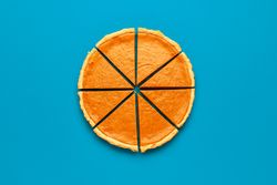 Sliced pumpkin pie top view, on a blue table
