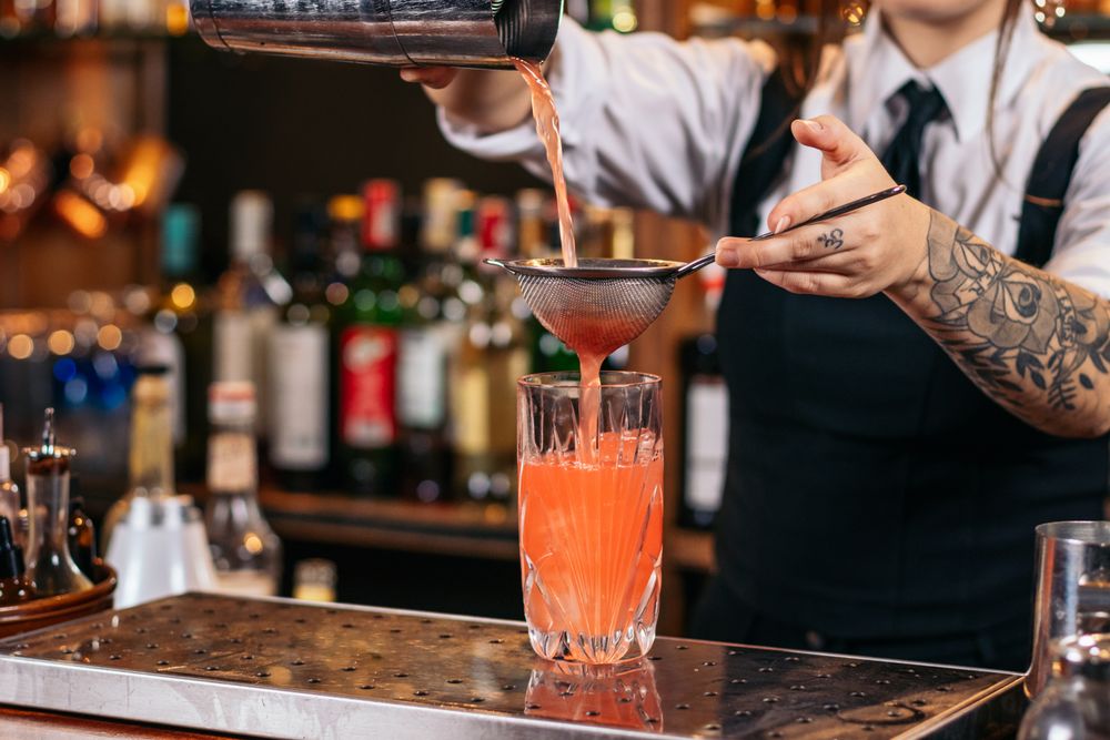 Female bartender preparing a cocktail in a traditional cocktail bar