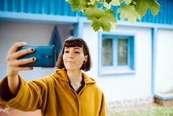 Woman taking selfie against countryside house