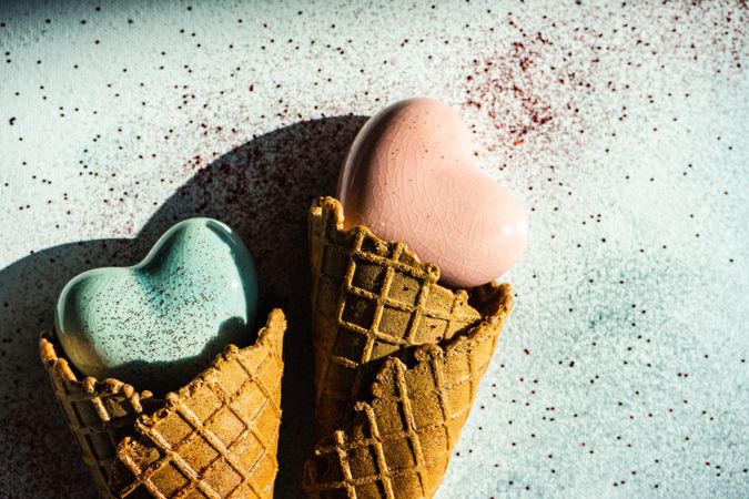 Two ceramic hearts in waffle cones on table with glitter