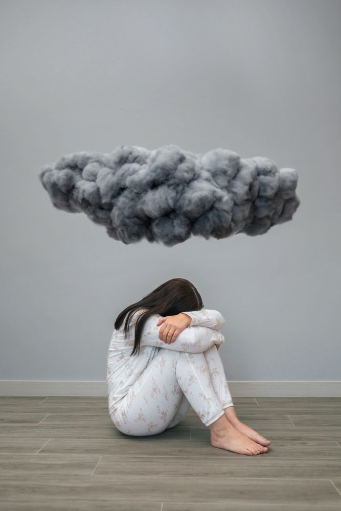 Woman crying under a dark storm cloud