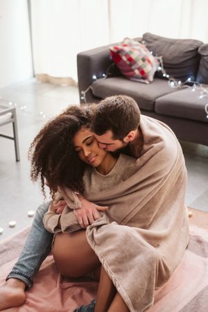 Multiethnic couple hugging on floor at home