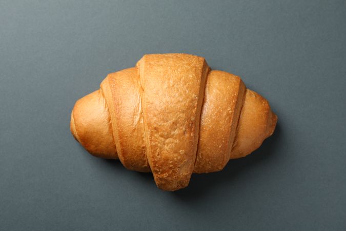 Freshly baked croissant on dark grey background, top view
