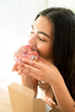 Happy woman in sundresses with box of glazed desserts