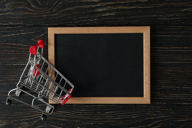 Shop cart and chalkboard on wooden background